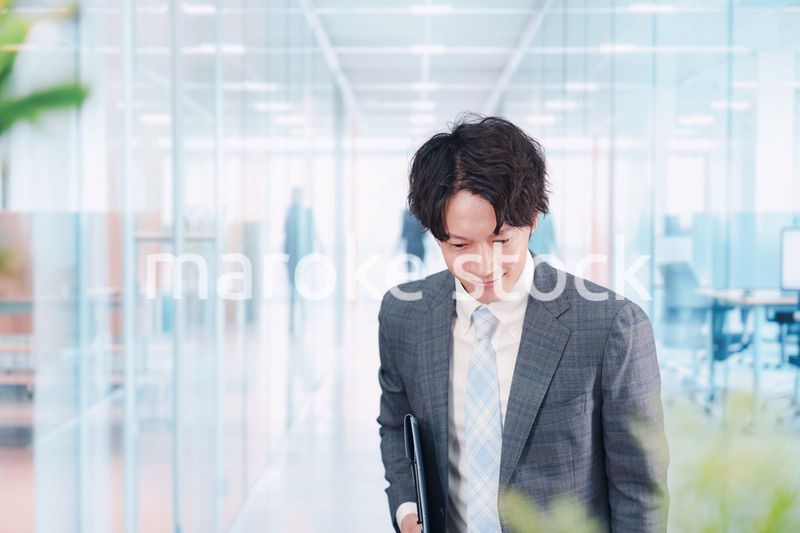 ガラス張りのオフィスの入口でお辞儀をする男性