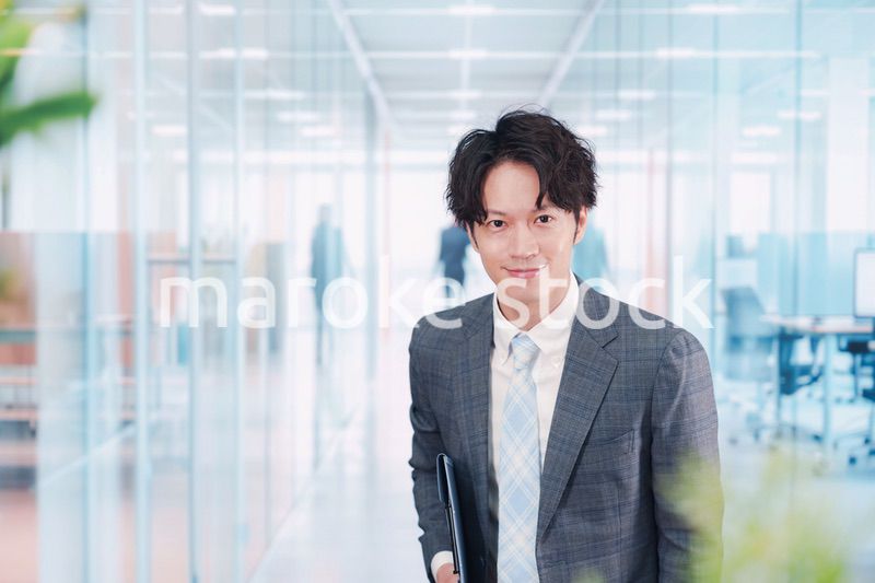 ガラス張りのオフィスの入口でお辞儀をする男性