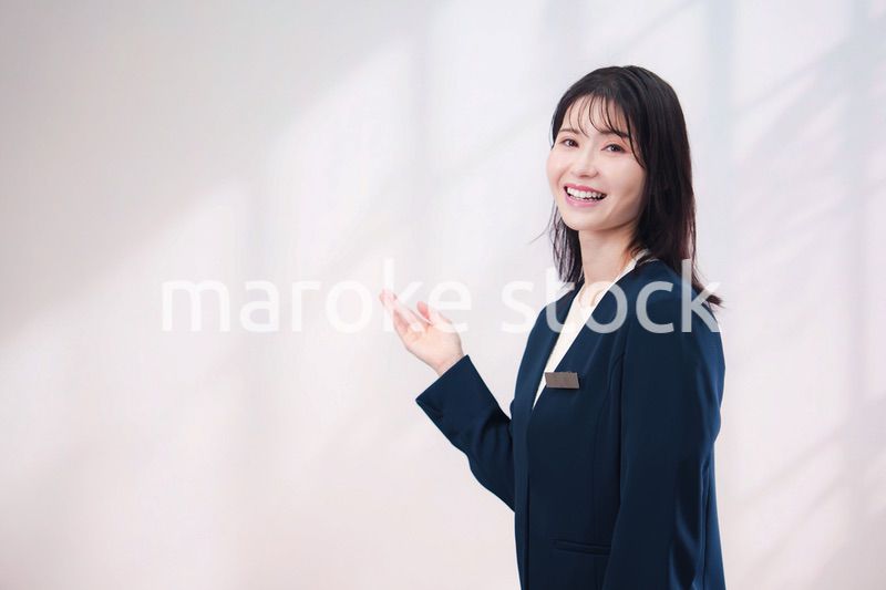 名札をつけて笑顔で接客をする若い女性（シンプル背景）
