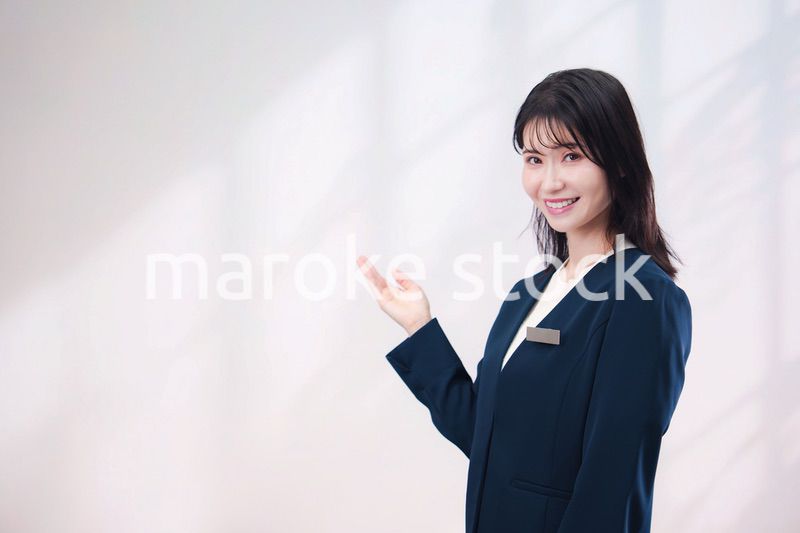 名札をつけて笑顔で接客をする若い女性（シンプル背景）