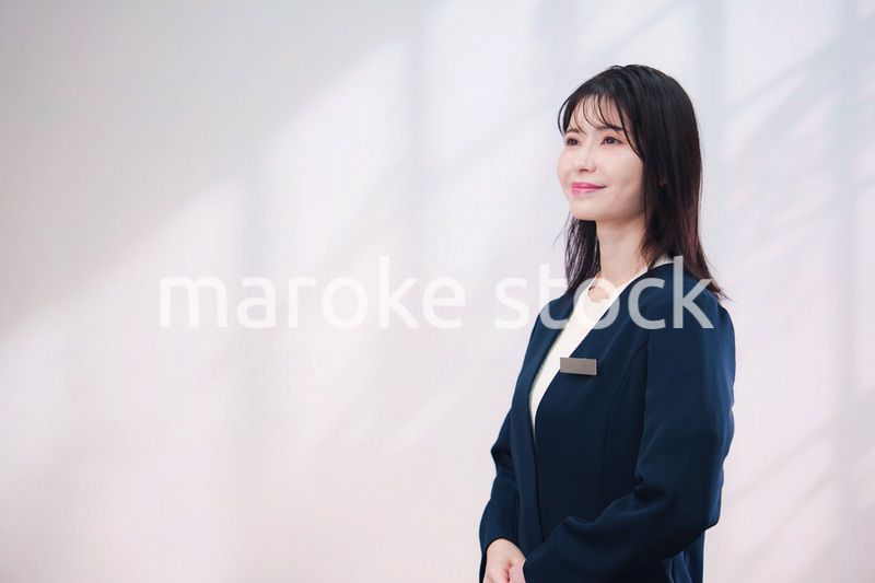 名札をつけて笑顔で接客をする若い女性（シンプル背景）
