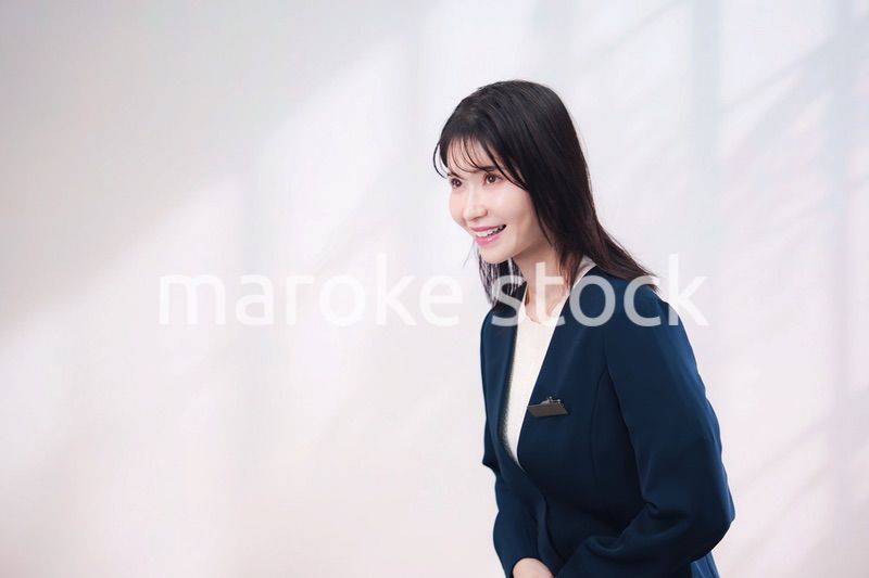 名札をつけて笑顔で接客をする若い女性（シンプル背景）