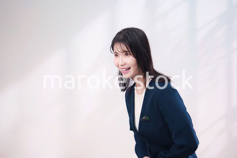 名札をつけて笑顔で接客をする若い女性（シンプル背景）