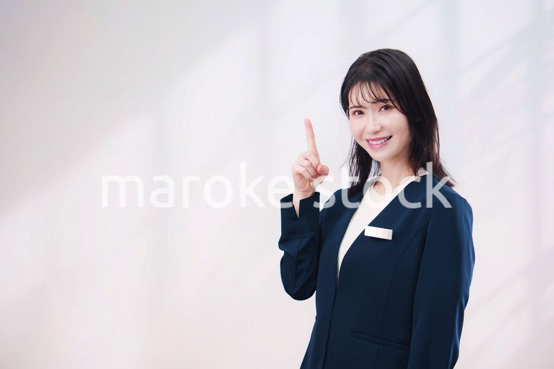 名札をつけて笑顔で接客をする若い女性（シンプル背景）