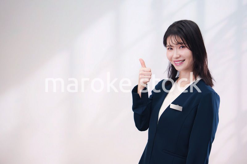 名札をつけて笑顔で接客をする若い女性（シンプル背景）