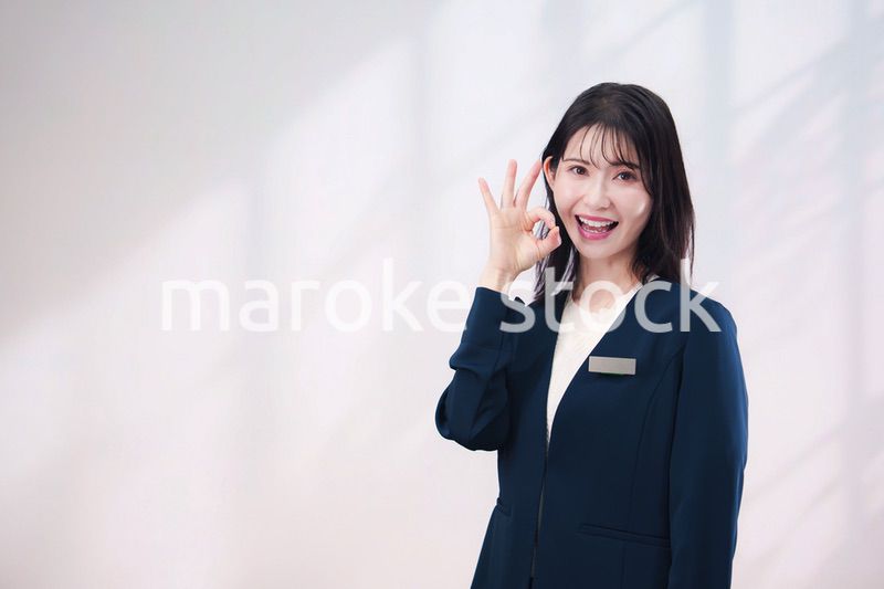 名札をつけて笑顔で接客をする若い女性（シンプル背景）