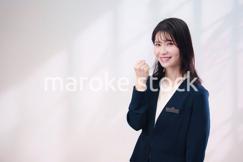 名札をつけて笑顔で接客をする若い女性（シンプル背景）