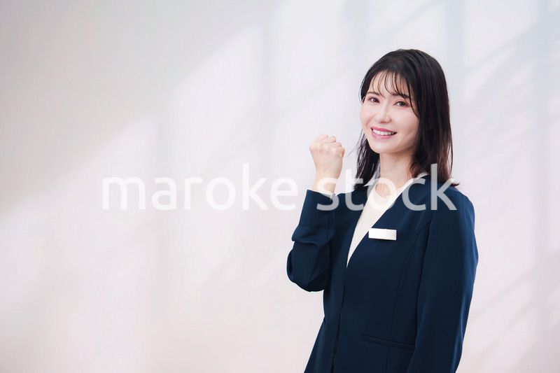 名札をつけて笑顔で接客をする若い女性（シンプル背景）