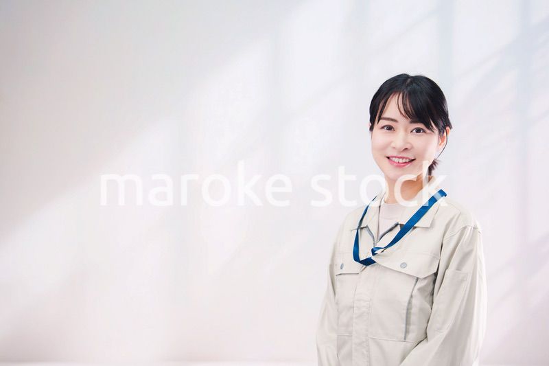 作業服を着て笑顔の若い女性（シンプル背景）