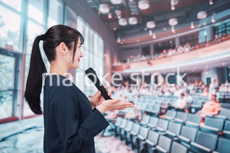 ホールで司会をする若い女性