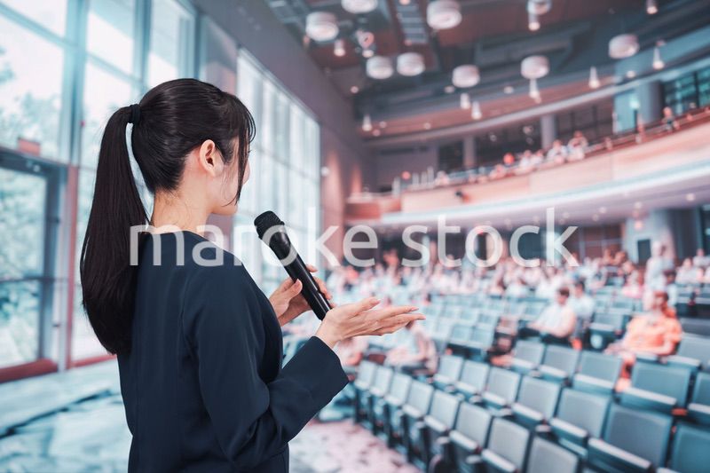 ホールで司会をする若い女性