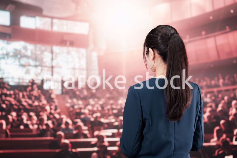 大勢の聴衆の前で話す女性