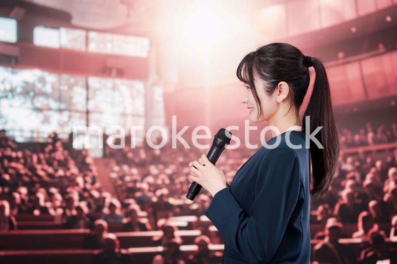 大勢の聴衆の前で話す女性