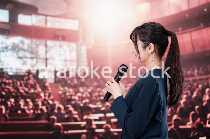 大勢の聴衆の前で話す女性