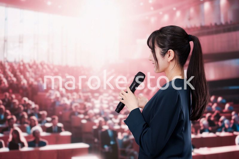 大勢の聴衆の前で話す女性