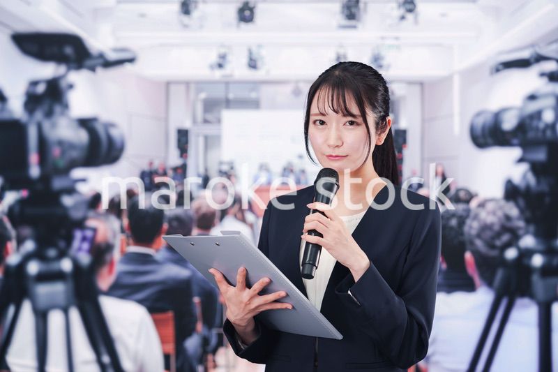 記者会見場からレポートをする女性記者