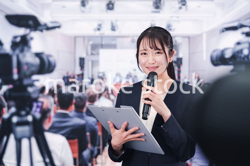 記者会見場からレポートをする女性記者