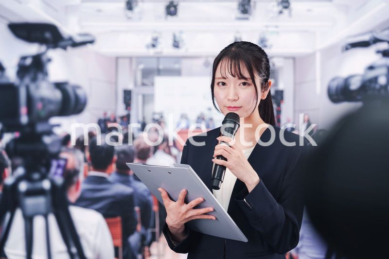 記者会見場からレポートをする女性記者