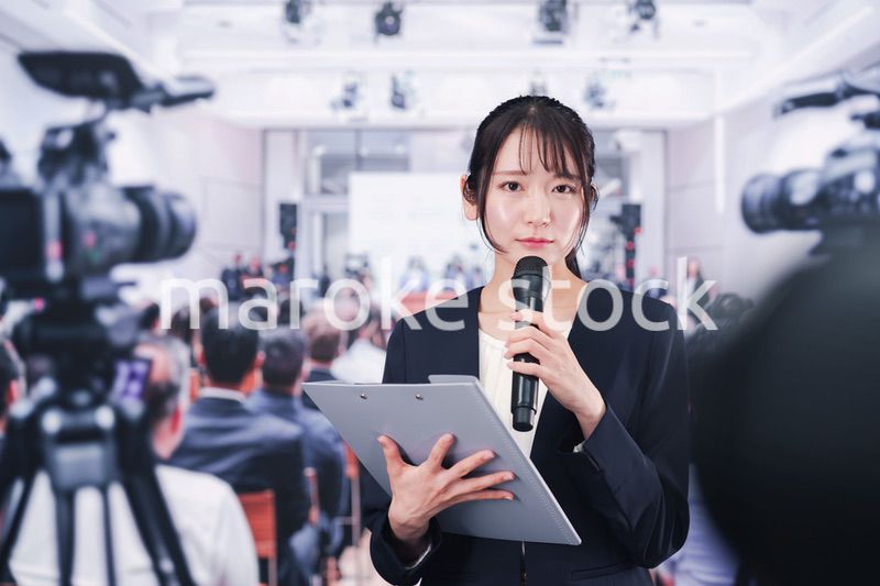 記者会見場からレポートをする女性記者