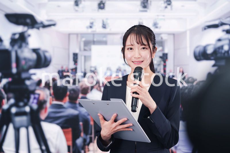 記者会見場からレポートをする女性記者