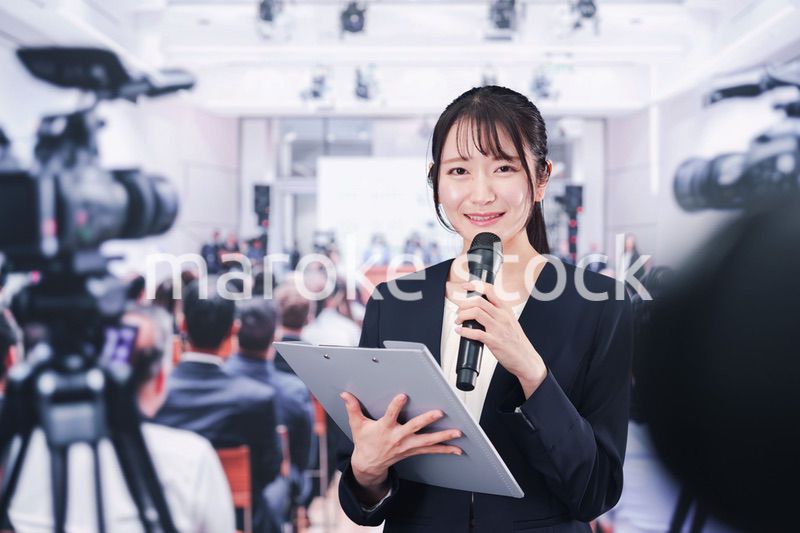 記者会見場からレポートをする女性記者