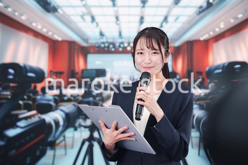 記者会見場からレポートをする女性記者