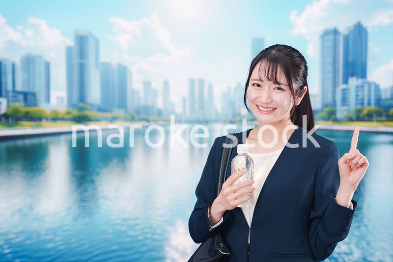 ペットボトルを持って笑顔で通勤をする若い女性