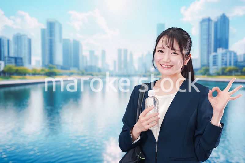 ペットボトルを持って笑顔で通勤をする若い女性