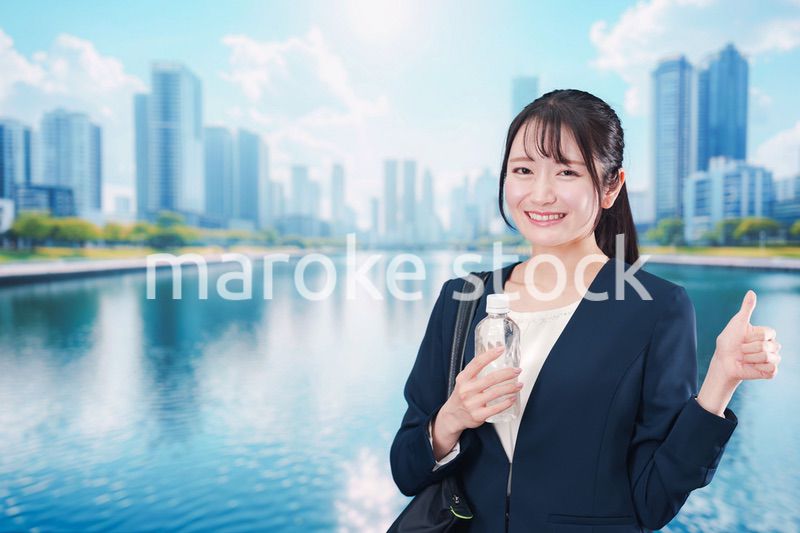ペットボトルを持って笑顔で通勤をする若い女性