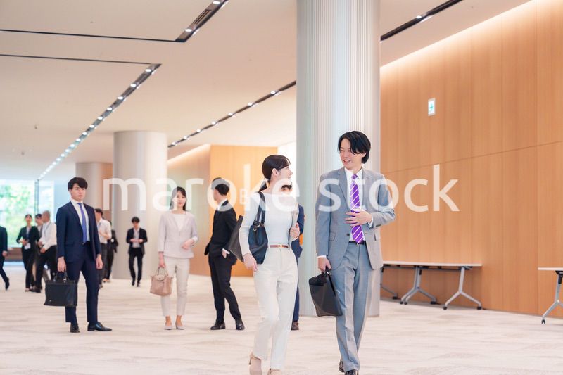 オフィスのホールで話しながら歩くビジネスパーソン