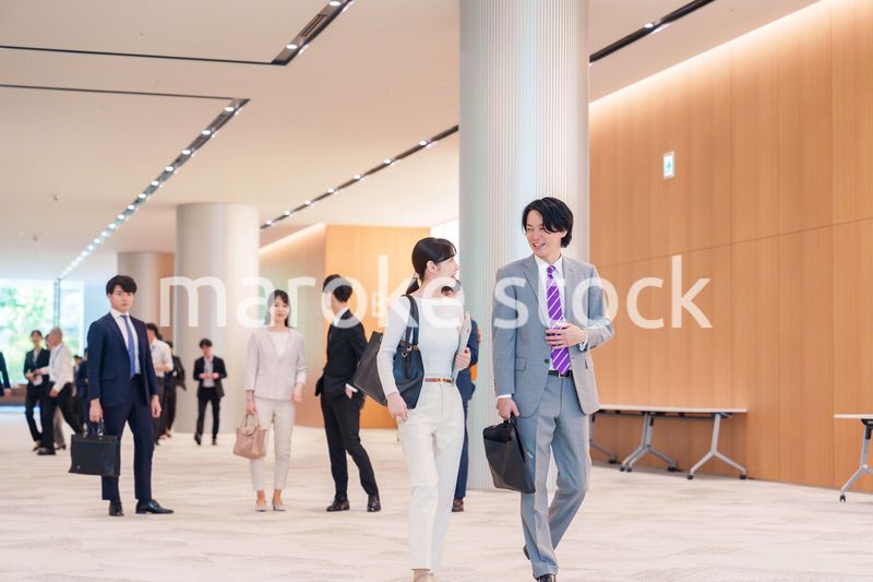 オフィスのホールで話しながら歩くビジネスパーソン