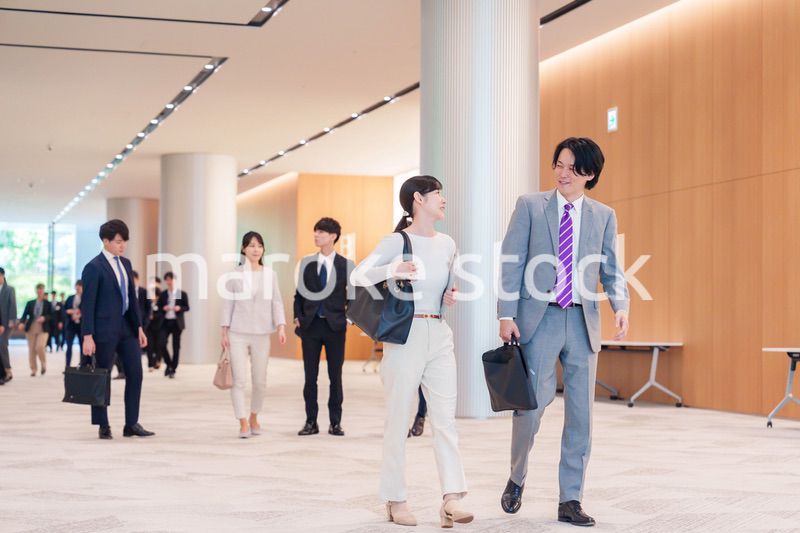オフィスのホールで話しながら歩くビジネスパーソン