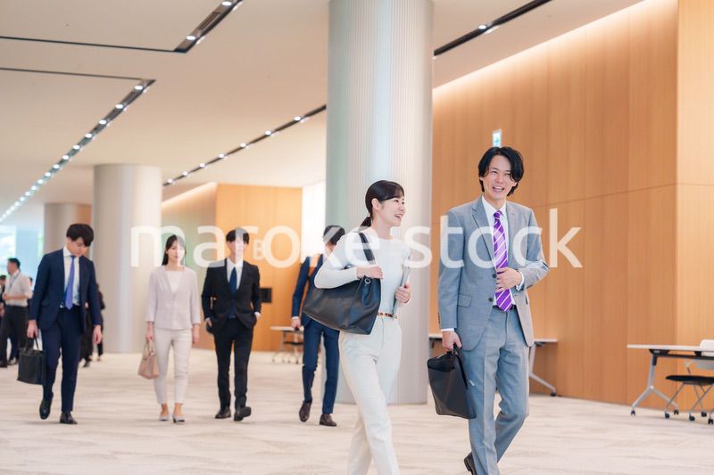 オフィスのホールで話しながら歩くビジネスパーソン