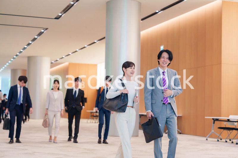 オフィスのホールで話しながら歩くビジネスパーソン