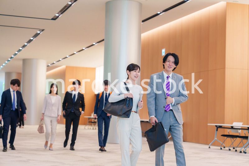オフィスのホールで話しながら歩くビジネスパーソン