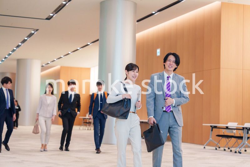 オフィスのホールで話しながら歩くビジネスパーソン