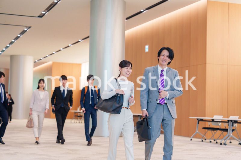 オフィスのホールで話しながら歩くビジネスパーソン