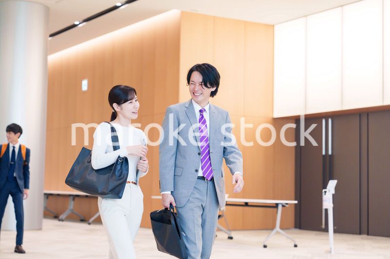 オフィスのホールで話しながら歩くビジネスパーソン