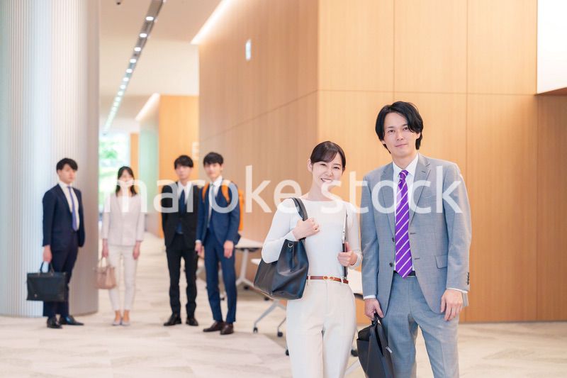 オフィスのホールで話しながら歩くビジネスパーソン