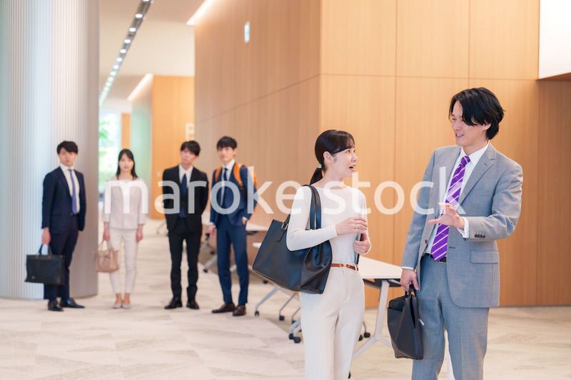オフィスのホールで話しながら歩くビジネスパーソン
