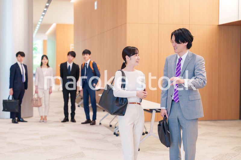 オフィスのホールで話しながら歩くビジネスパーソン