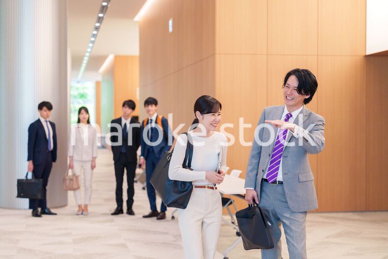 オフィスのホールで話しながら歩くビジネスパーソン