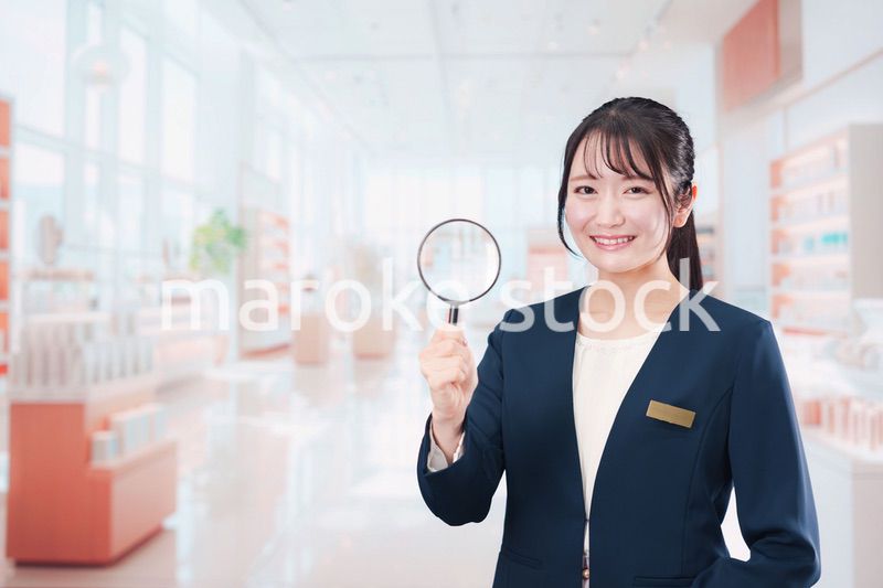 笑顔でルーペを持つ美容部員の女性