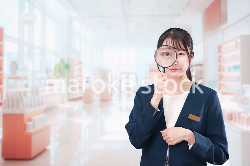 笑顔でルーペを持つ美容部員の女性
