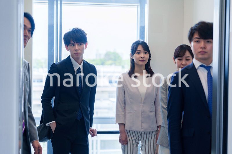 オフィスでエレベーターに乗るビジネスパーソン