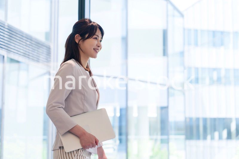 オフィスの中で笑顔で歩くビジネスウーマン