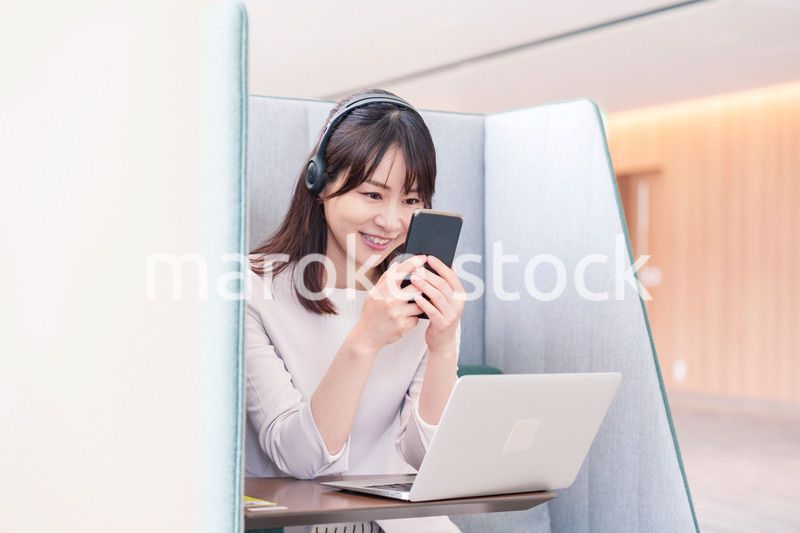 リモート会議をサボってスマホを使う若いビジネスパーソン