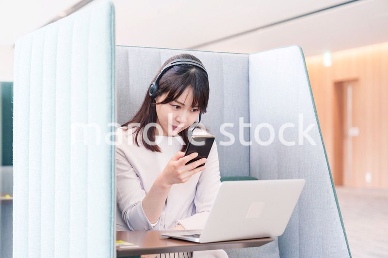 リモート会議をサボってスマホを使う若いビジネスパーソン