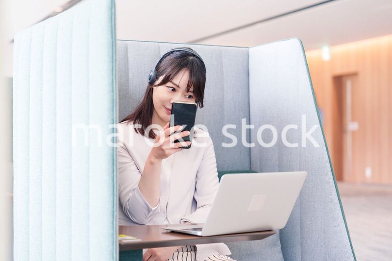 リモート会議をサボってスマホを使う若いビジネスパーソン