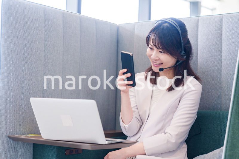 リモート会議をサボってスマホを使う若いビジネスパーソン